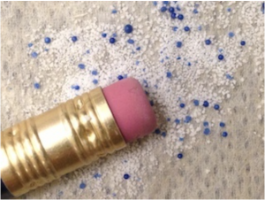 the blue and white microbeads are about the one one-hundreth of the size of a pencil eraser