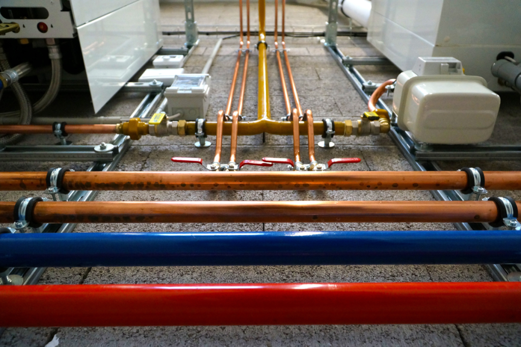 Plumbing pipes running along a concrete floor
