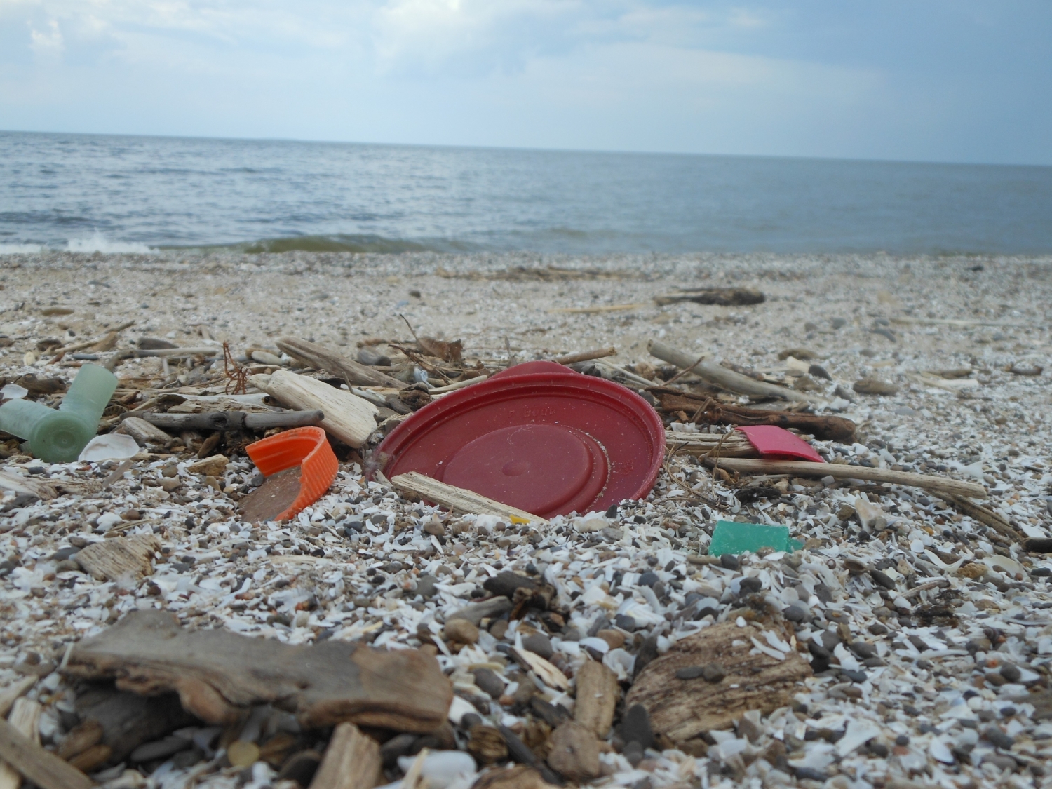 Plastic debris on a beach with water in the background.
